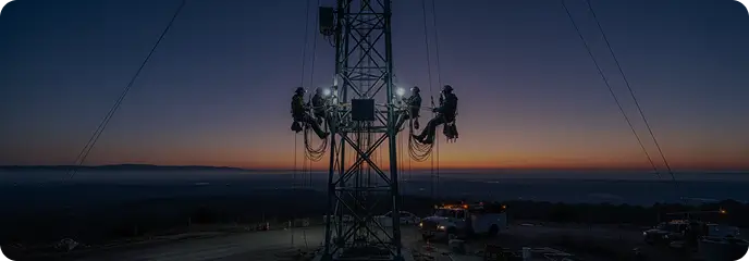 Techniker an einem Telekommunikationsmast in der Dämmerung